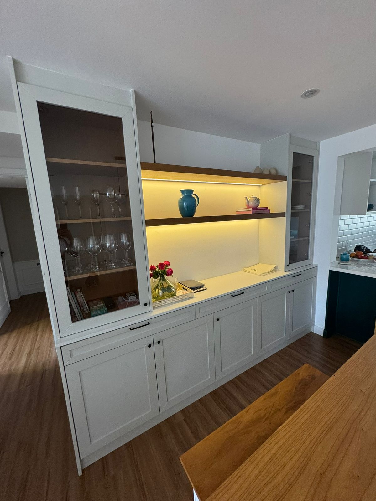 Buffet branco com vitrines de vidro, prateleiras iluminadas e detalhes em madeira